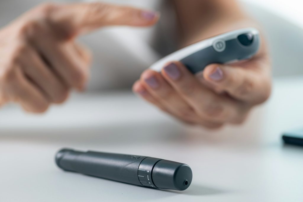 A woman tracks glucose levels and inputs data via smartphone, vital for diabetes management