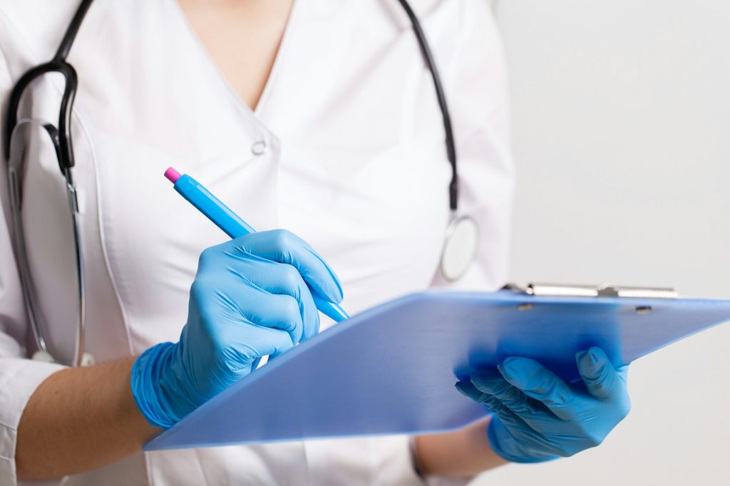 Doctor writes down patient medical history with pen on card