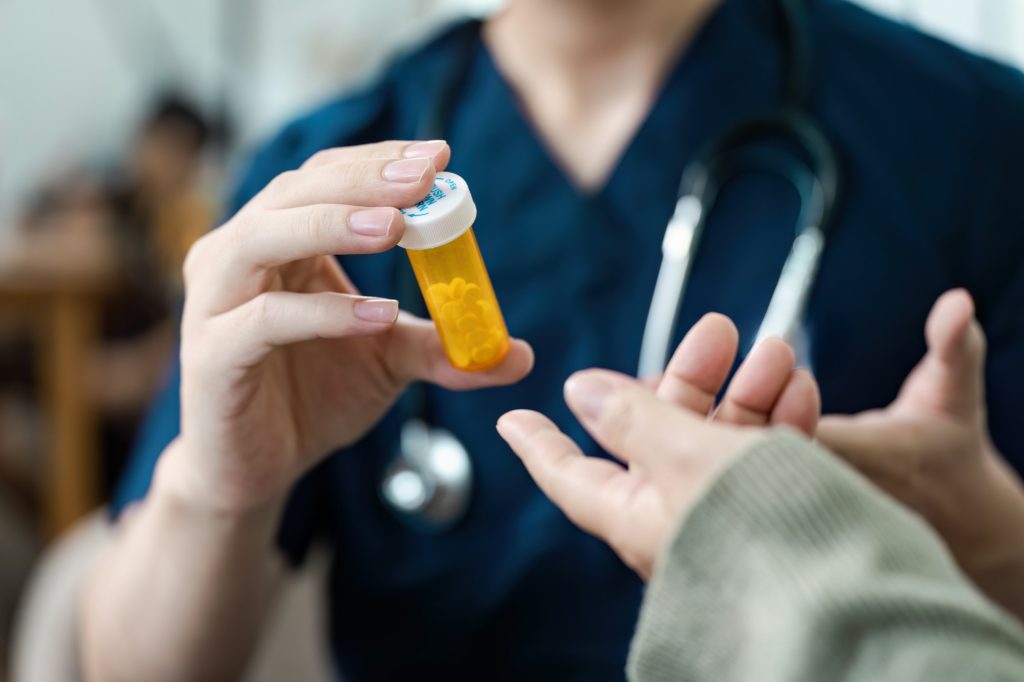 Healthcare Professional Handing Prescription Medication to Patient in Medical Setting