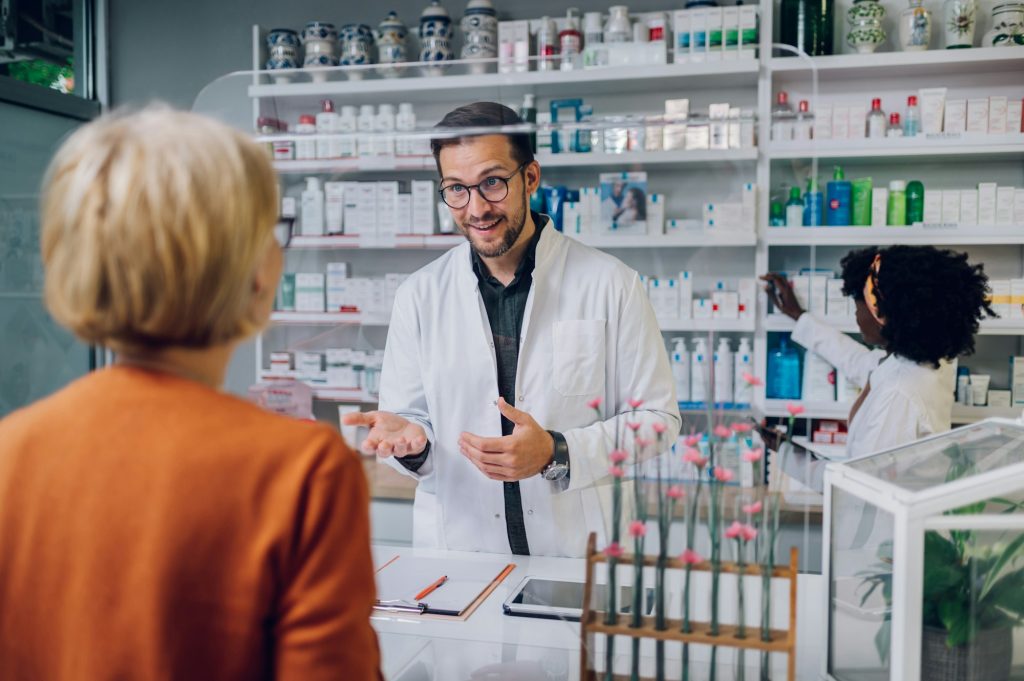 Portrait of a male pharmacist working at the counter in pharmacy and selling drugs